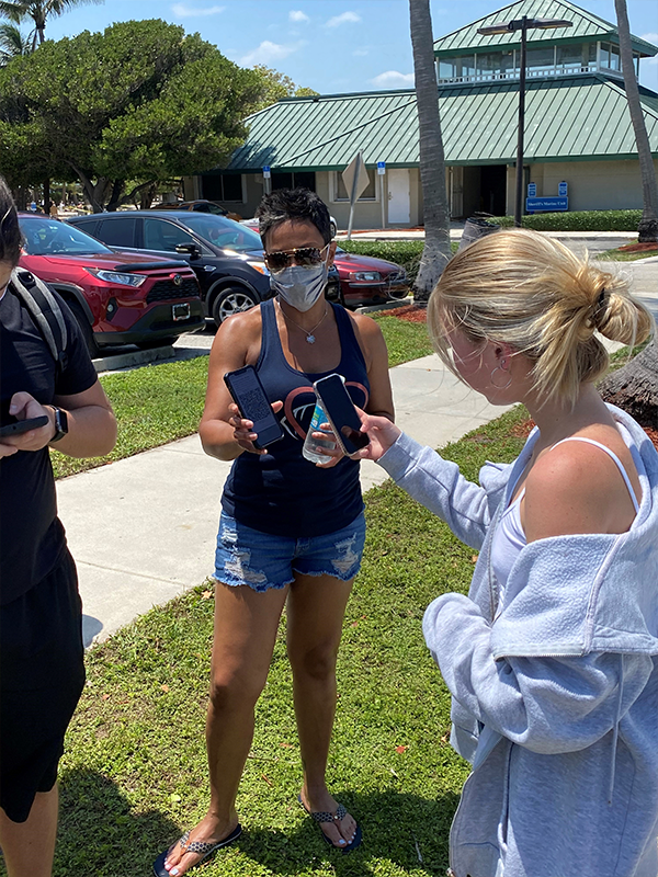 Head of School at Score Academy holding her phone in a car park. The CAT QR code is loaded on her phone for students to scan and check in.